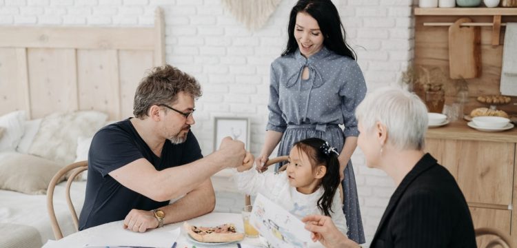 Child with foster parents and a social worker discussing adoption at home.