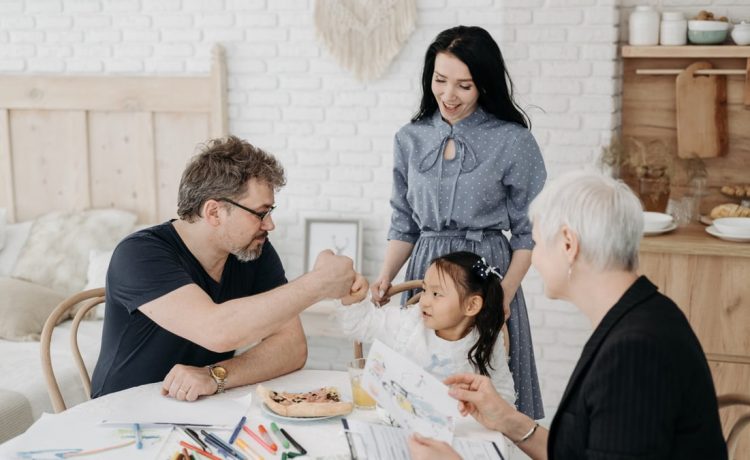 Child with foster parents and a social worker discussing adoption at home.